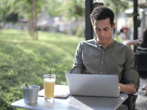 person using a laptop sitting at an outdoor table