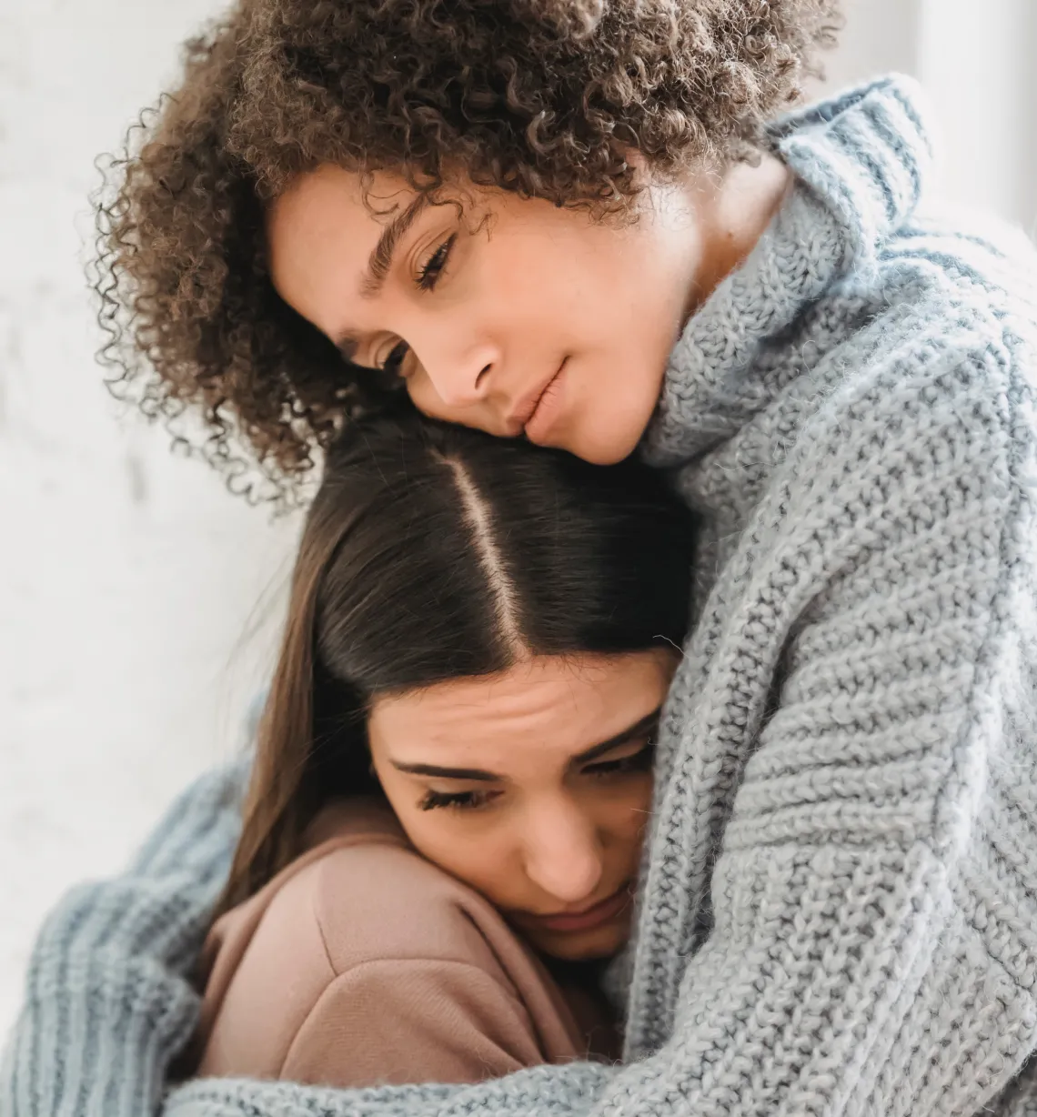 two people hugging and looking to the side