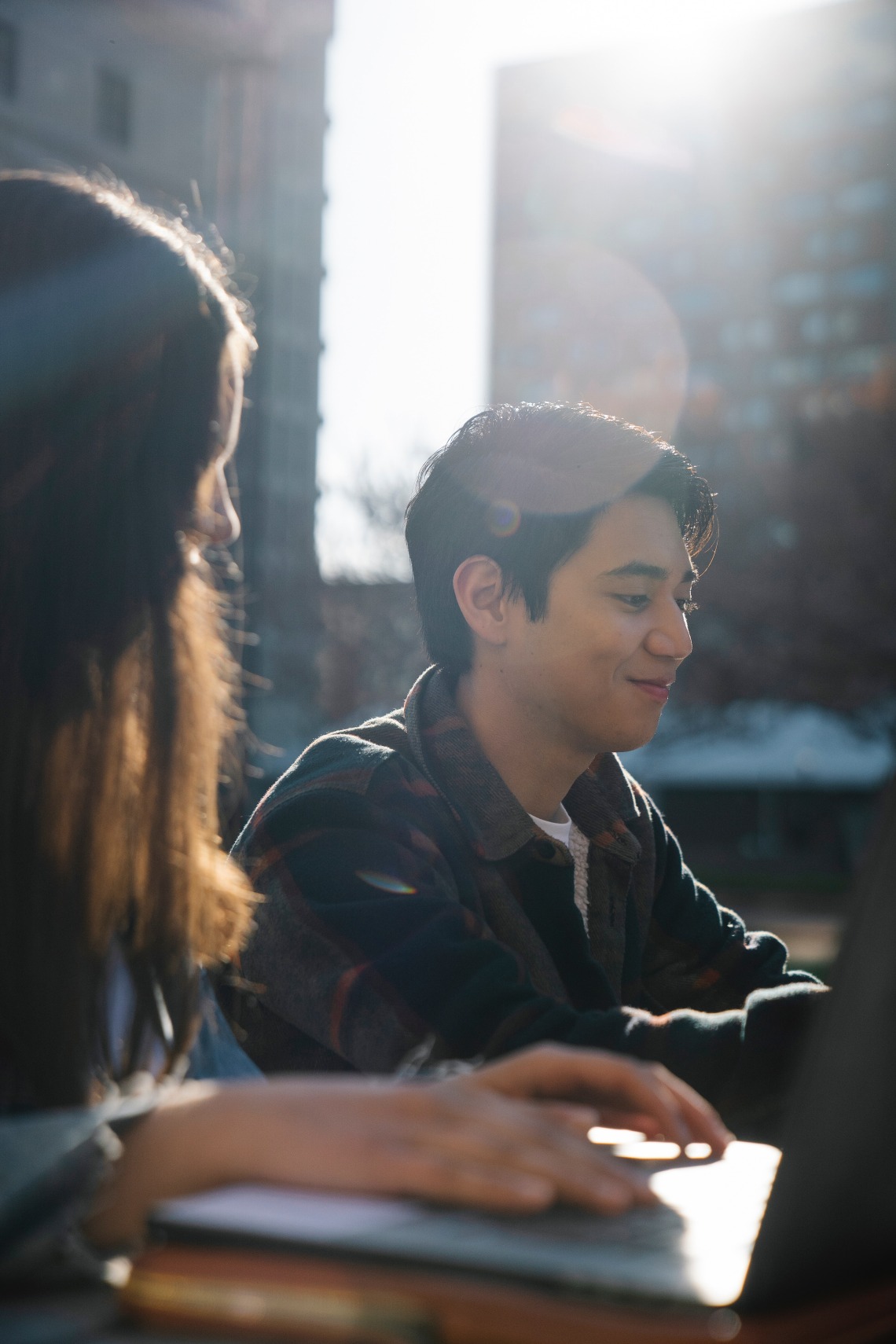photograph of two college-aged students sitting outside with the sunlight shining on them