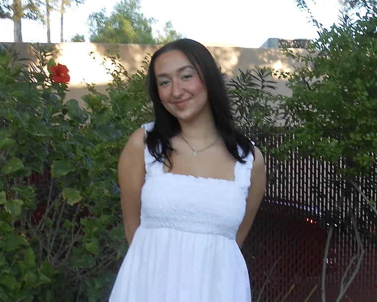 headshot of a person standing outside with foliage visible in the background