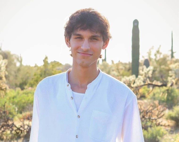 headshot of a person in front of an outdoor desert background